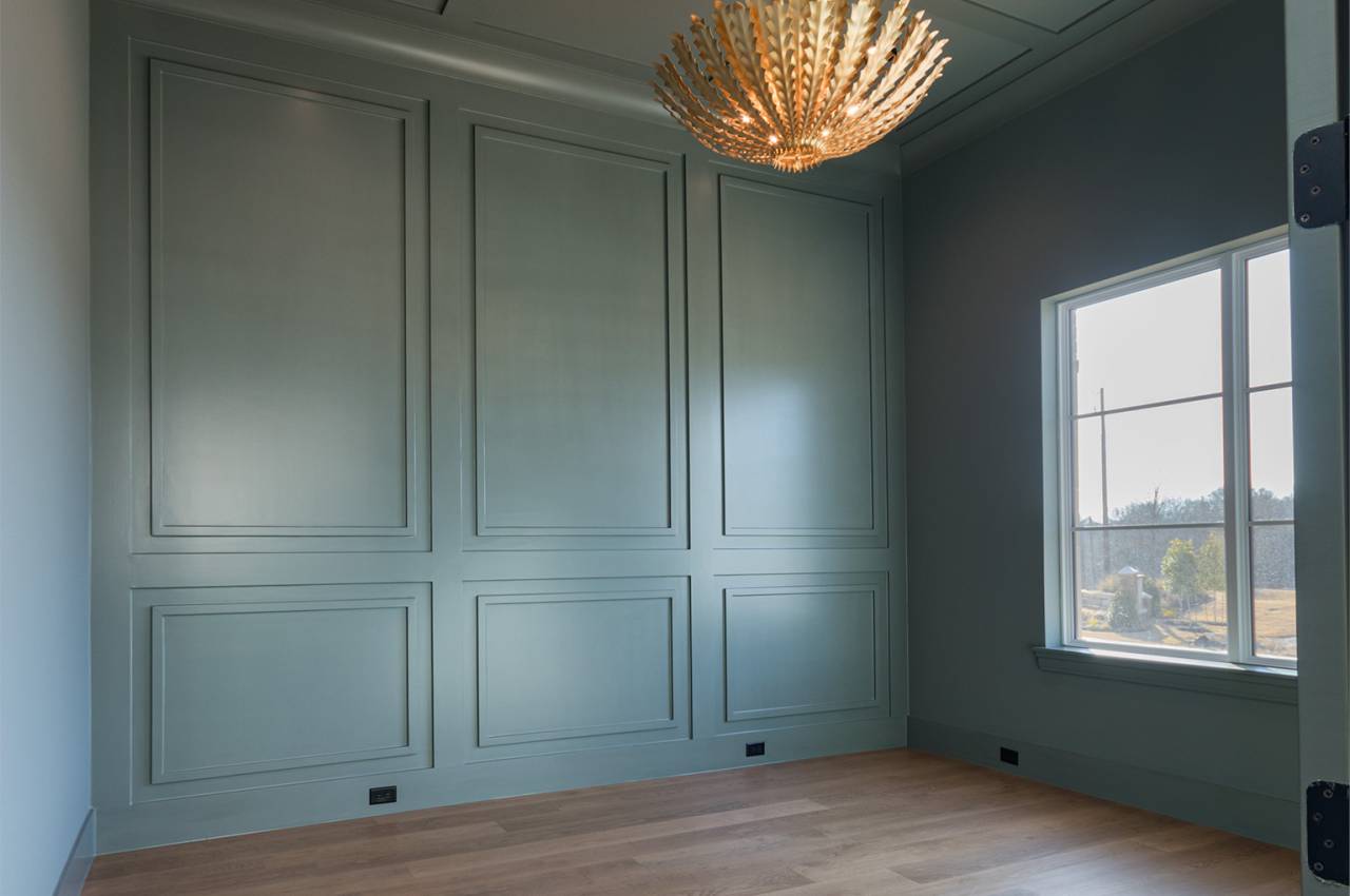 Paneled walls and ceiling in study with designer paint and decorative lighting.