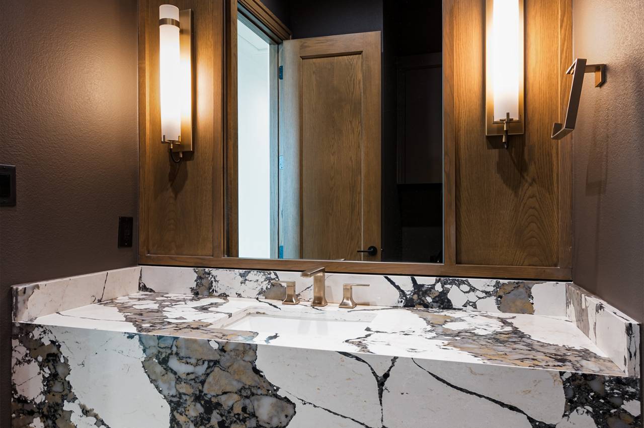 Designer powder bath near study with panel encased mirror and decorative lighting.