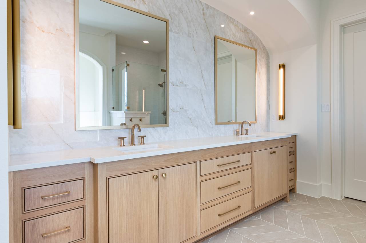 Primary bathroom with white oak cabinetry, double sinks, designer lighting and look at that backsplash!