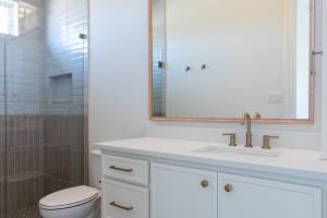 Another secondary bathroom with painted cabinets and earth tone tile floors and shower.