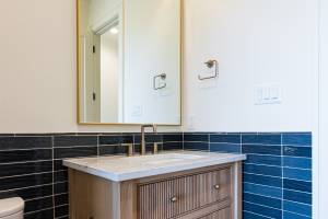 Pool bath is decorated with patterned, textured tile on the walls along with white oak, reeded cabinets.  What a designer touch!