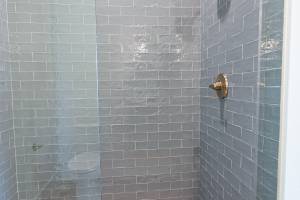 Matching shower with textured tiled walls and earth tone floor tile.