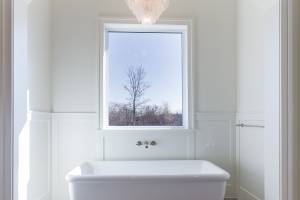 The primary bath features an inset, stand-alone tub surrounded by painted paneling and beautiful patterned floor tile with a gorgeous chandelier!